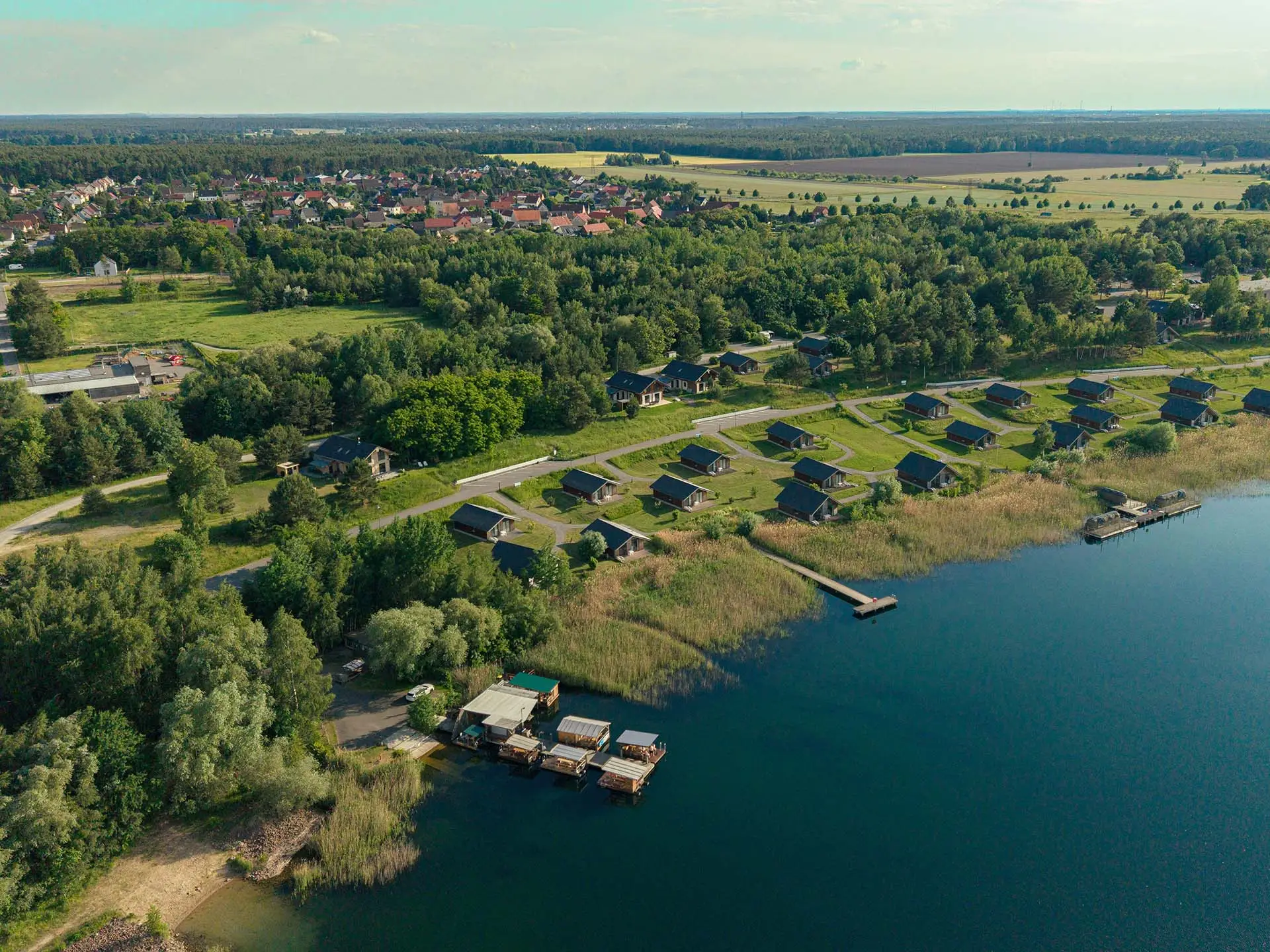 Luftaufnahme der Naturresidenz Ufertraum in ihrer Lage am Gröberner See, umgeben von Wald